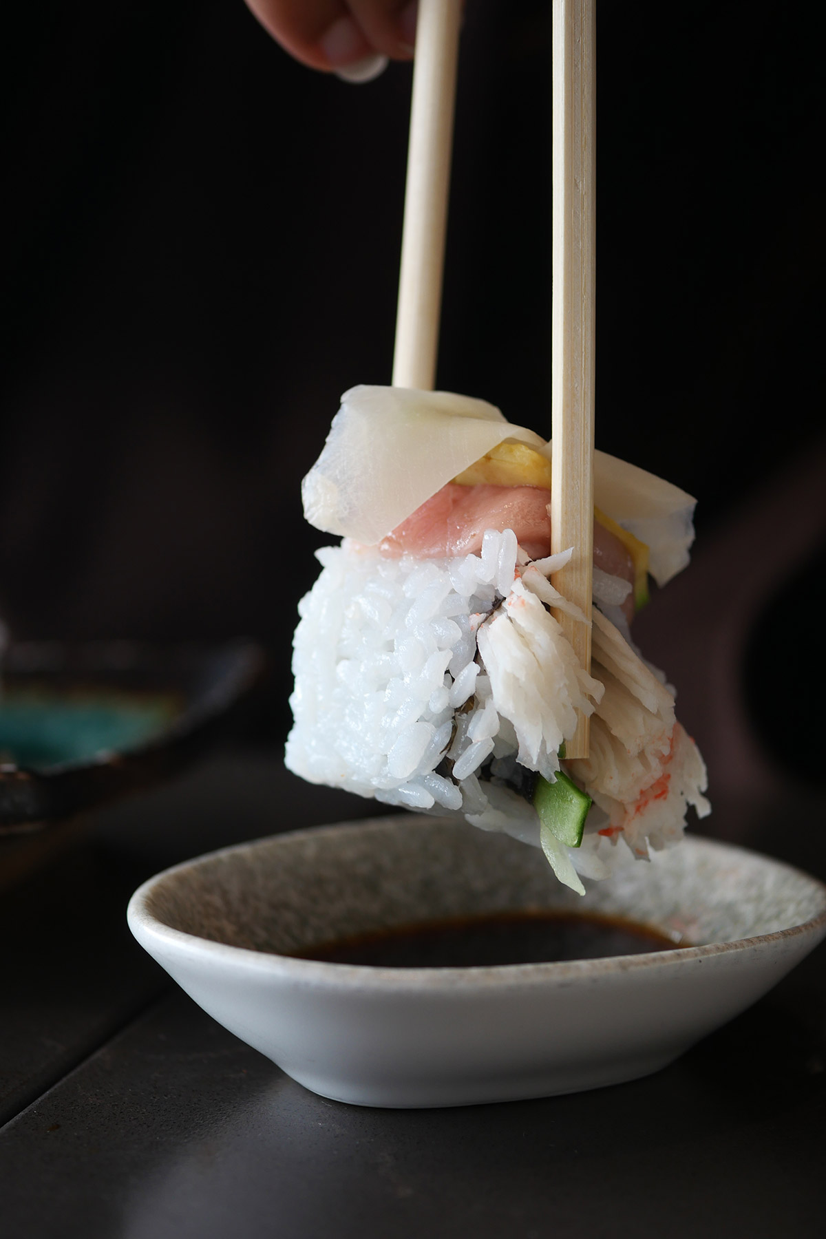 A guest at the counter lifting nigiri with chopsticks